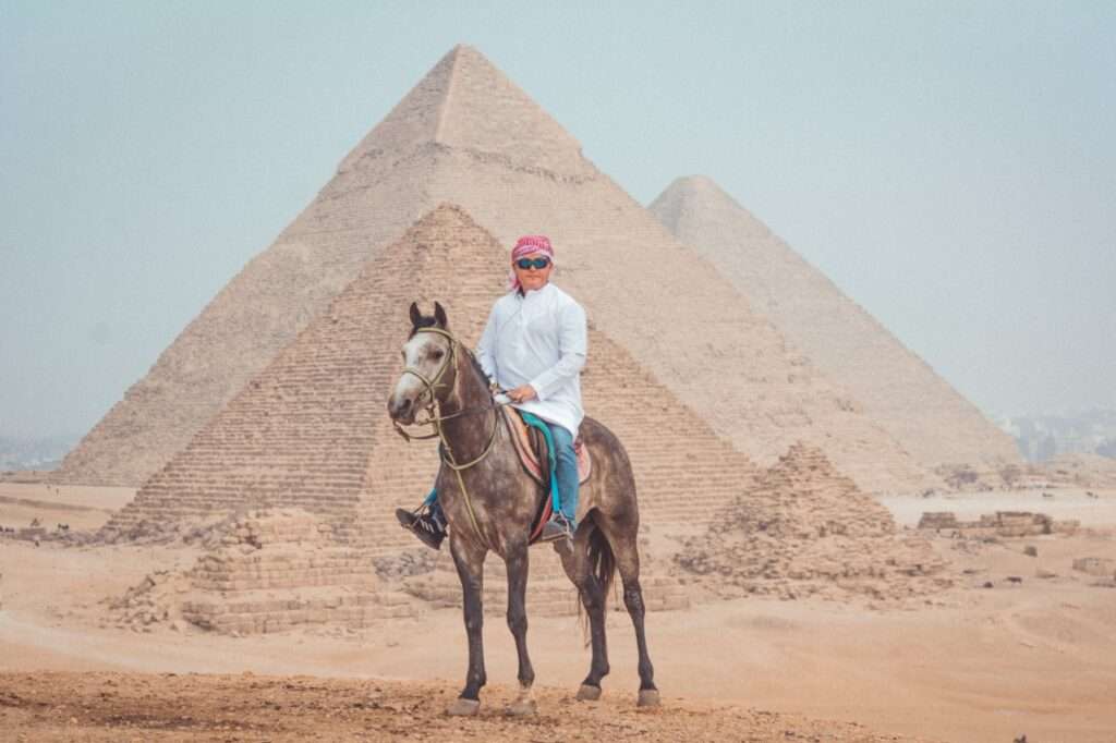 Rider on a grey Arabian horse in front of the Pyramids of Giza