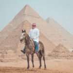 Rider on a grey Arabian horse in front of the Pyramids of Giza