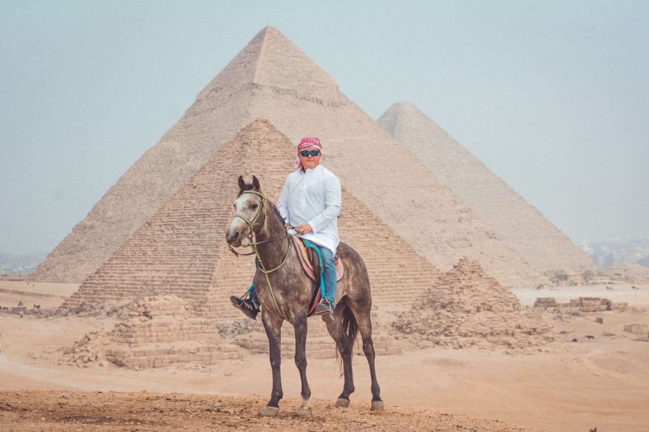 Rider on a grey Arabian horse in front of the Pyramids of Giza