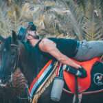 Rider relaxing on his horse under palm trees in Dahab