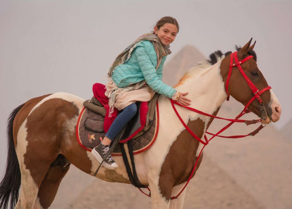Girl smiling on a pinto horse at the Giza Pyramids