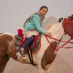 Girl smiling on a pinto horse at the Giza Pyramids