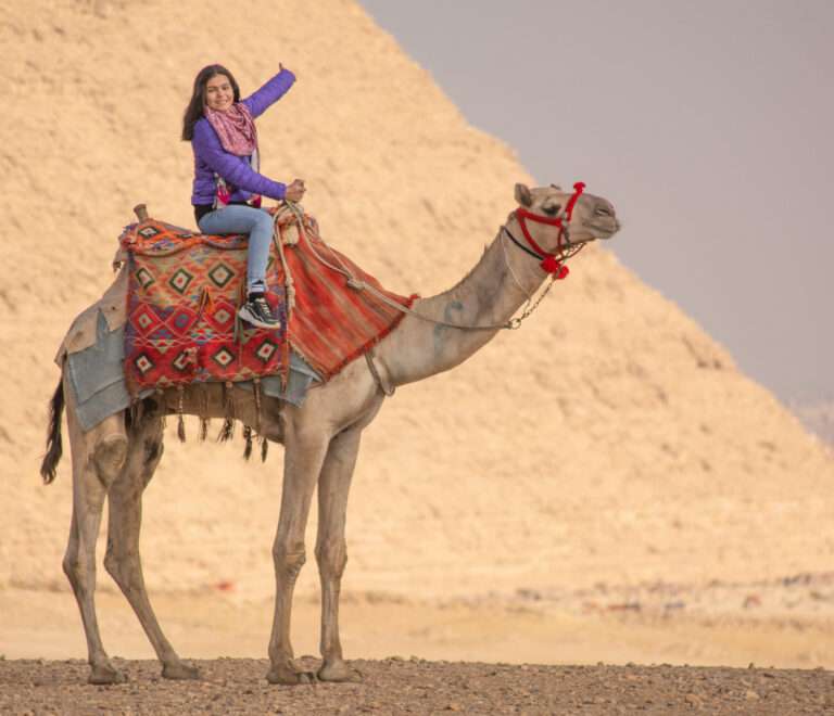 A cutie riding a camel.