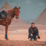 Rider sitting beside his horse facing the Giza Pyramids