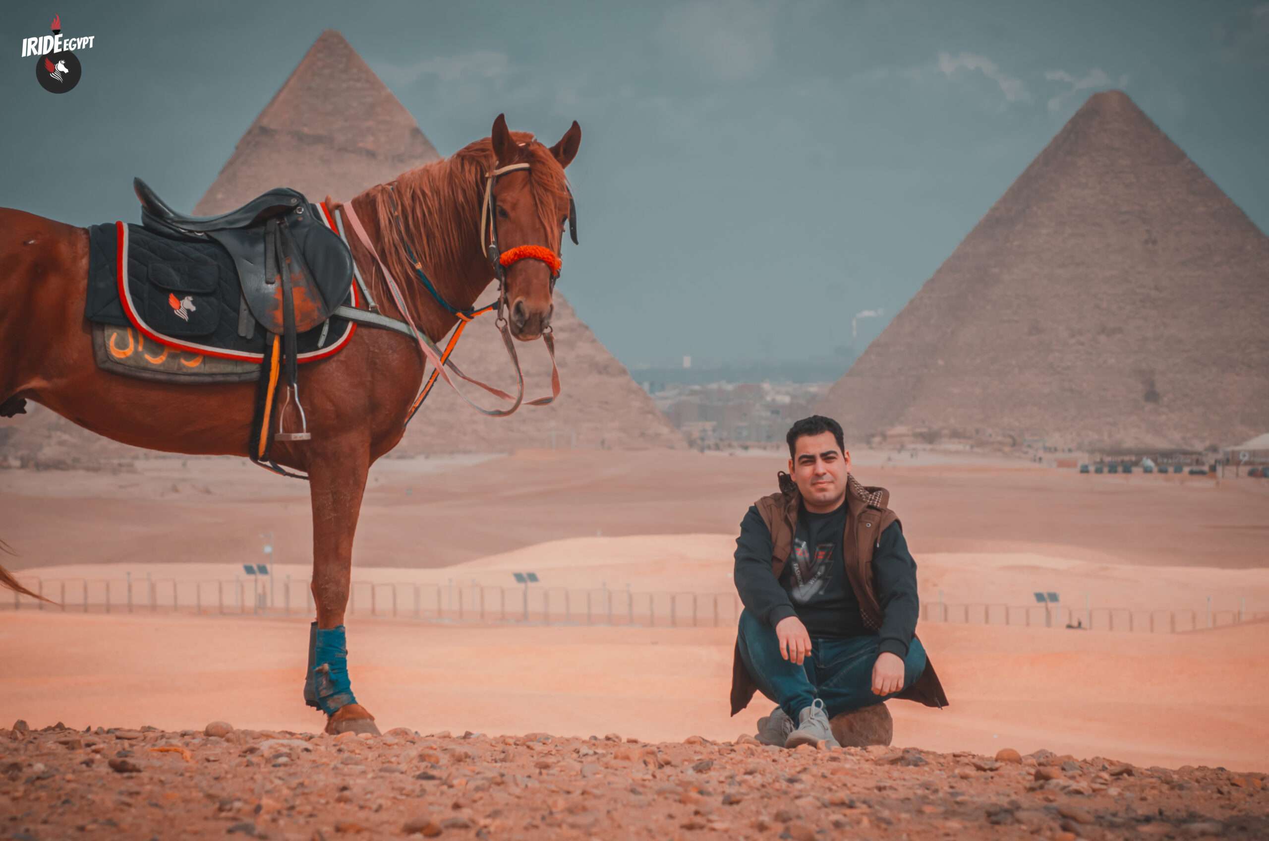 Rider sitting beside his horse facing the Giza Pyramids