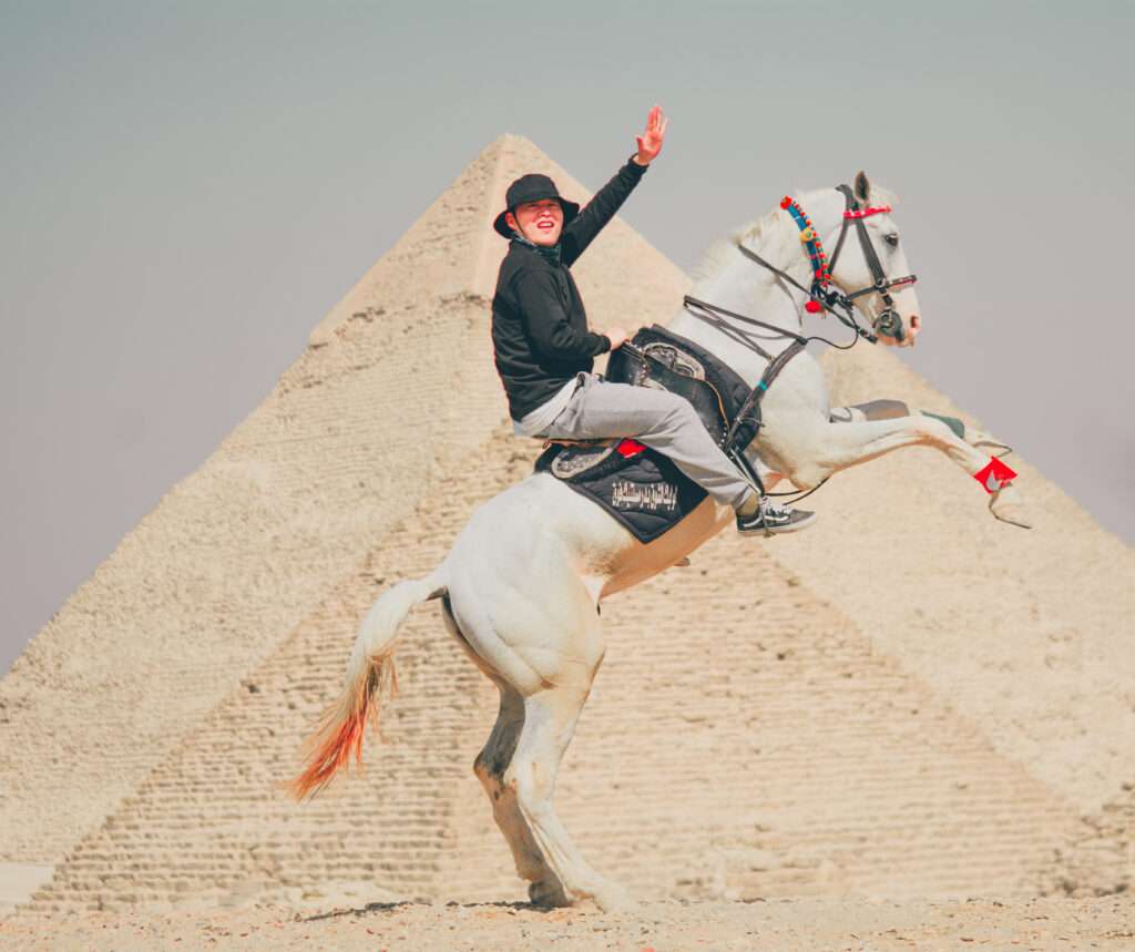 Rider on a rearing white horse in front of a pyramid