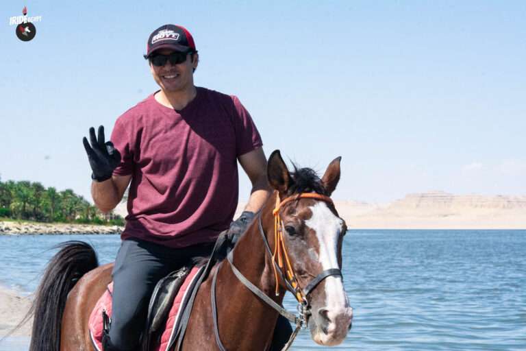 Rider waving from horseback on the shore of Lake Qarun