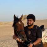 Smiling rider in a helmet with his horse in the Saqqara desert