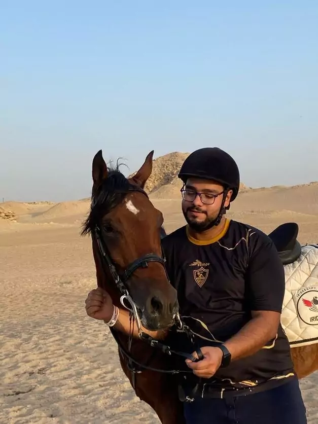 Smiling rider in a helmet with his horse in the Saqqara desert